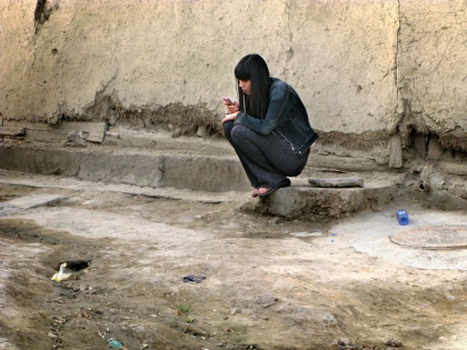  Mujer joven con el teléfono móvil en un callejón en la ciudad vieja, Boukhara, Ouzbekistan. ©Anne Barthélemy 